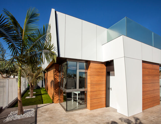 Casa moderna con paredes de madera y vidrio, destacando un diseño contemporáneo y elegante.